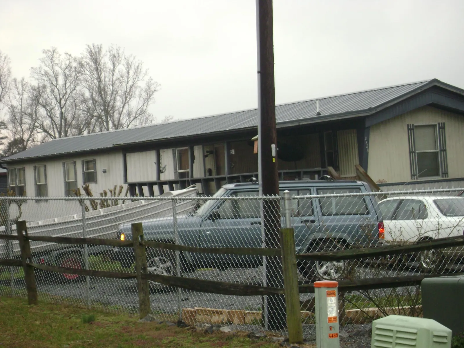Dark metal roof on a long single story building behind a chain link fence in Middlebury
