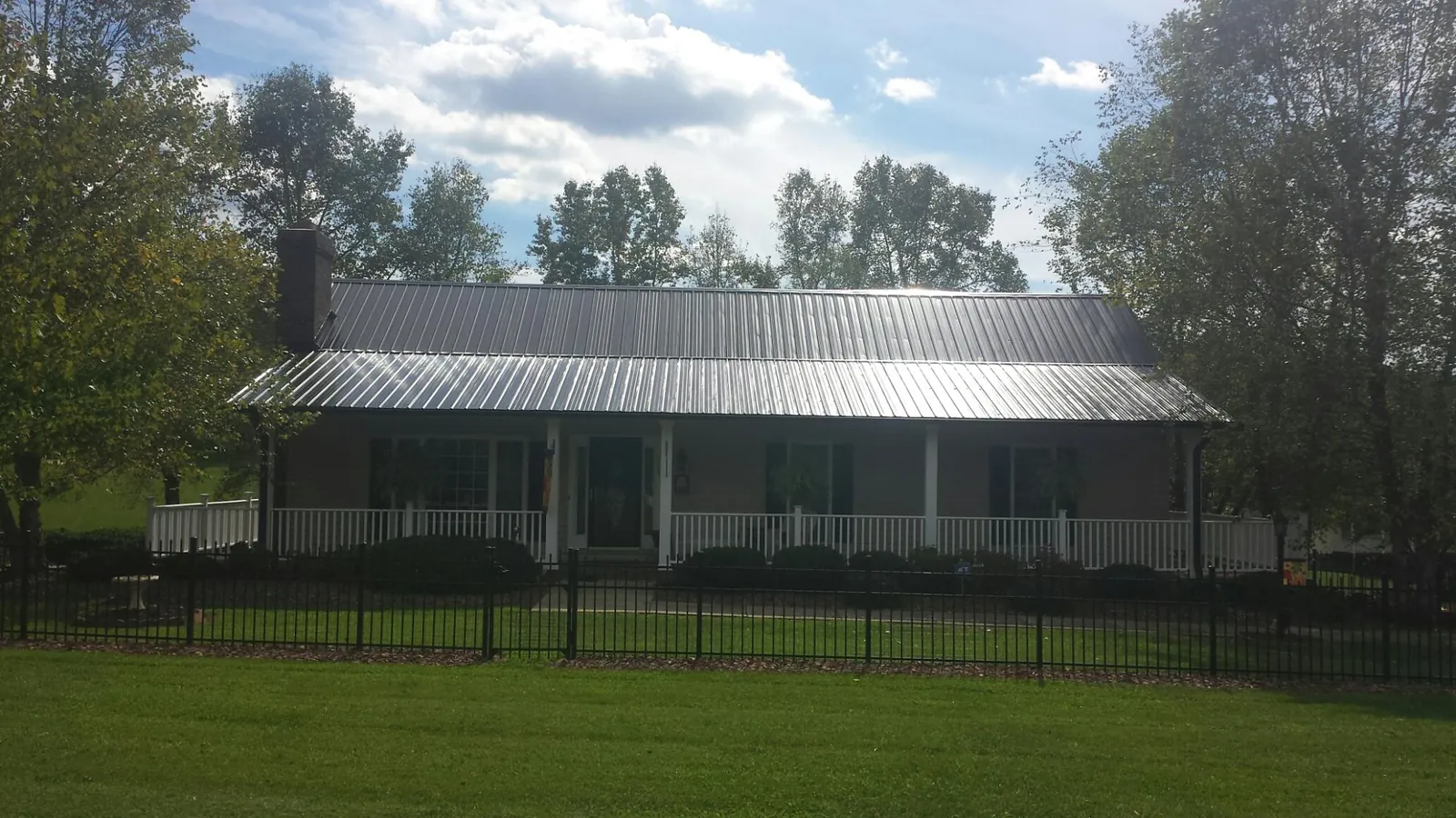 Gray metal roof on a brick ranch with a full width front porch — Gutter Guard Installation work by our crew in Middlebury